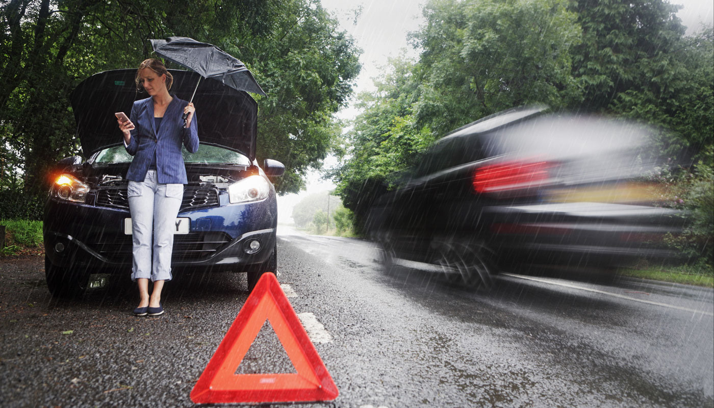 woman on side of road with broken down car