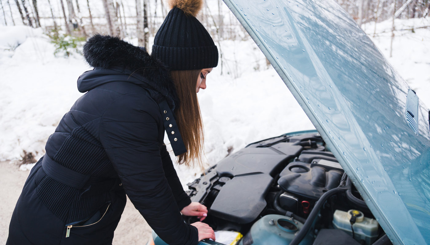 woman with her car hood up on the side of the road in the snow