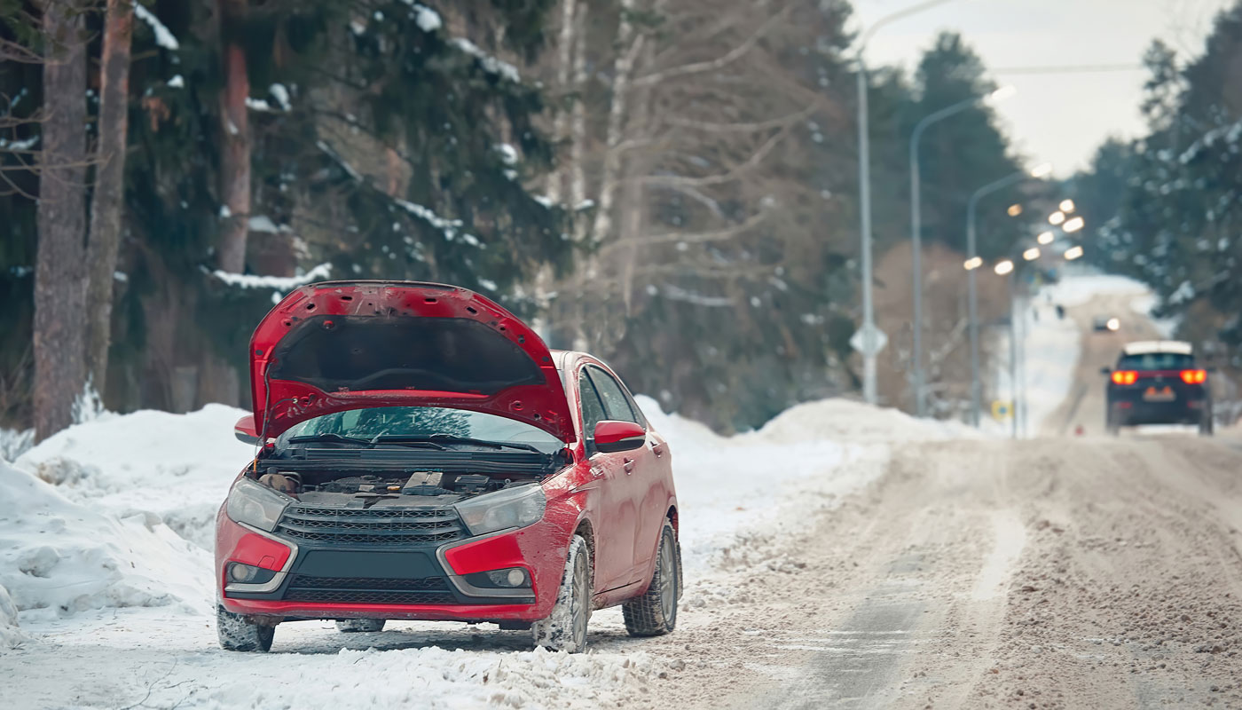 Broken down red car with raised hood on snowy roadside on cold winter day. Dangerous driving, car breakdown in cold weather. Broken car with raised hood