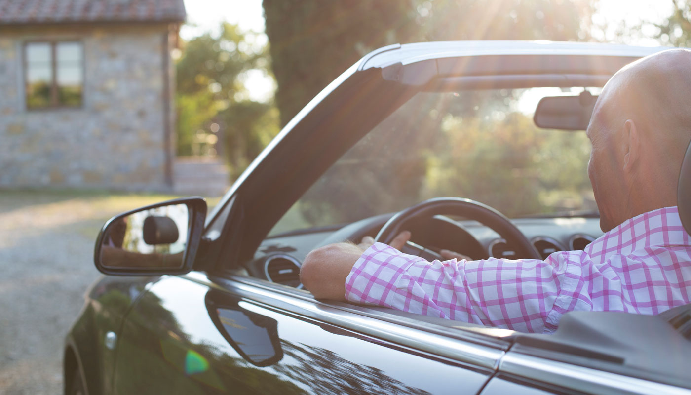 man riding in a convertible car