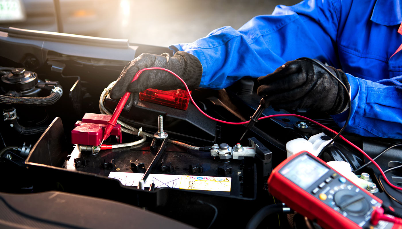 technician uses multimeter voltmeter to check voltage level in car battery. Service and Maintenance car battery.