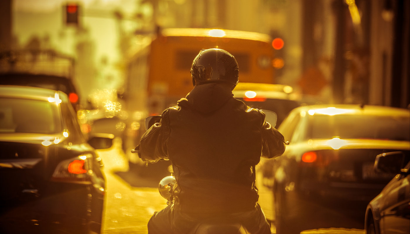 man riding motorcycle in heavy traffic with cars on each side