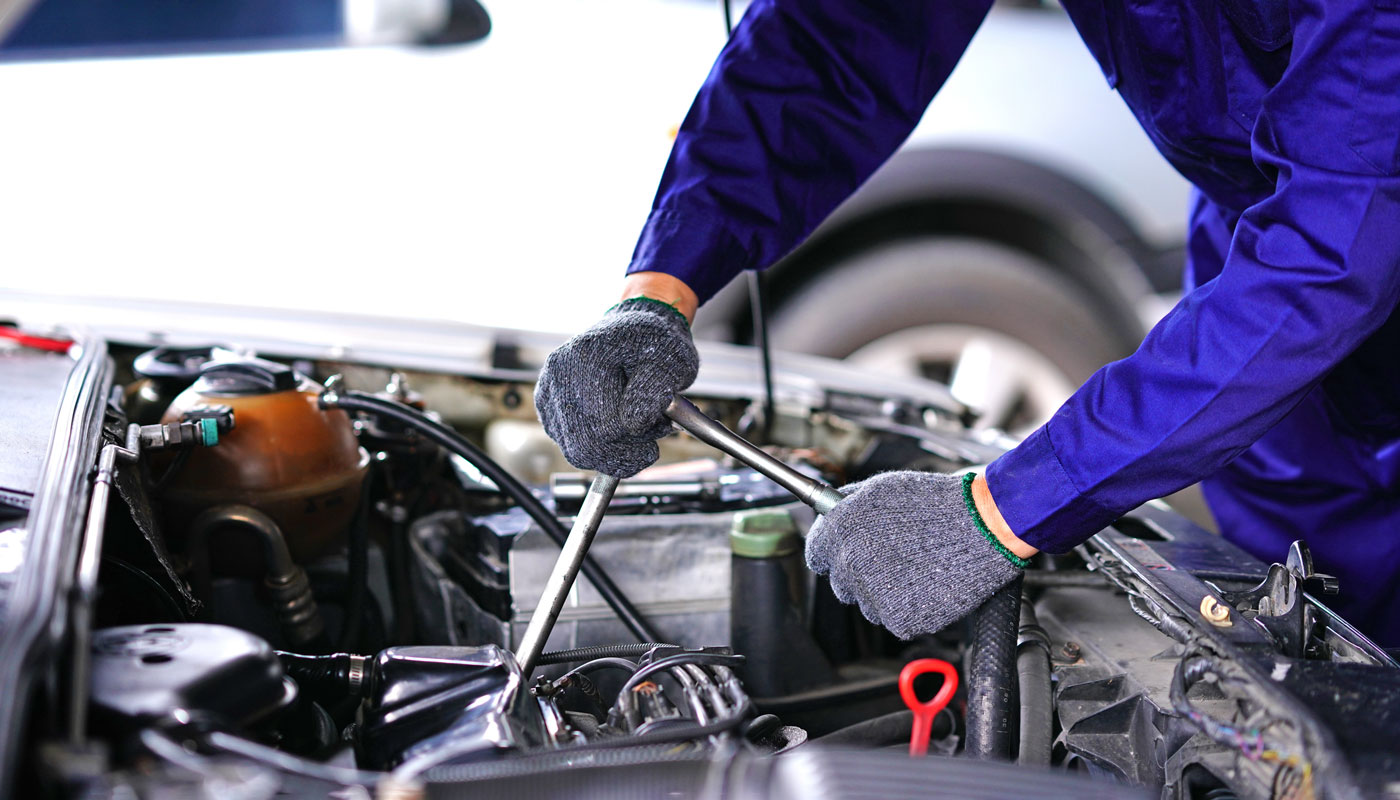 Mechanic working under the hood with gloves