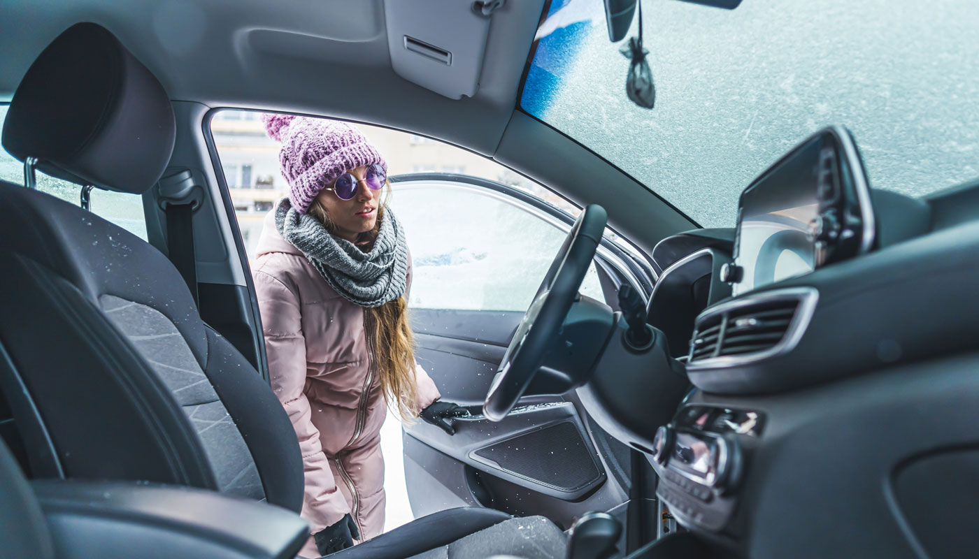 Woman in sunglasses peering into inside a car through the front door