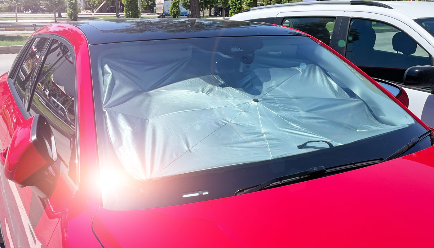 Red car in the direct sun with a sunshade covering the dashboard