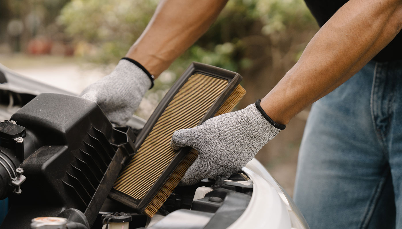 close-up of a man's hands replacing an air filter in a car engine, showcasing DIY maintenance and automotive care