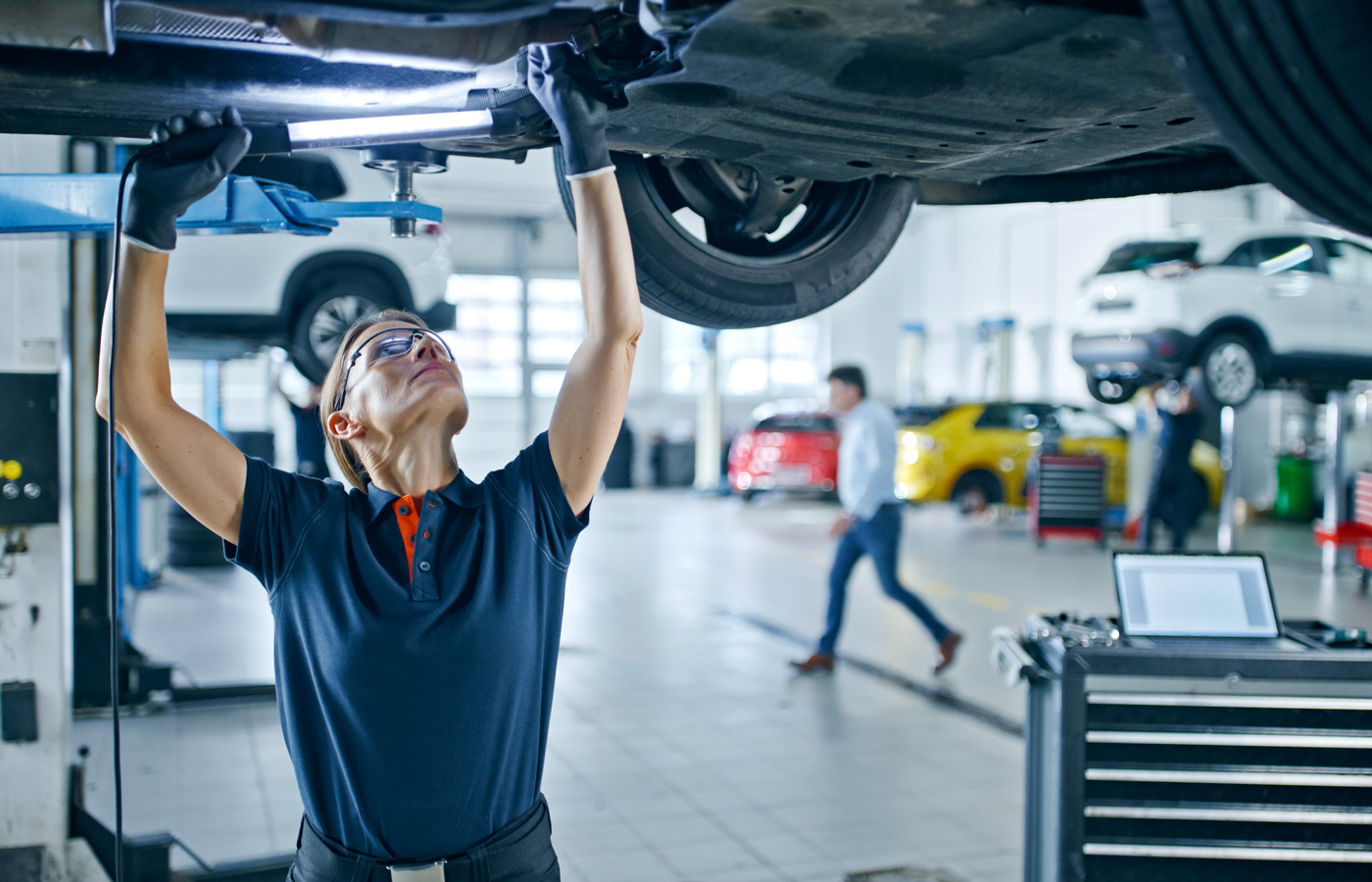 woman mechanic working under a car in a shop