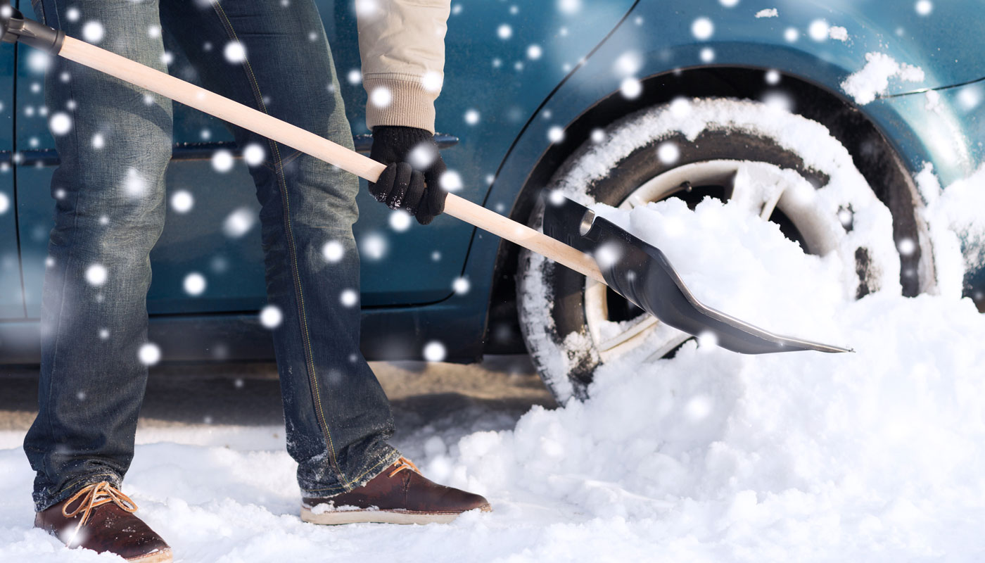 closeup of man digging snow with shovel near car