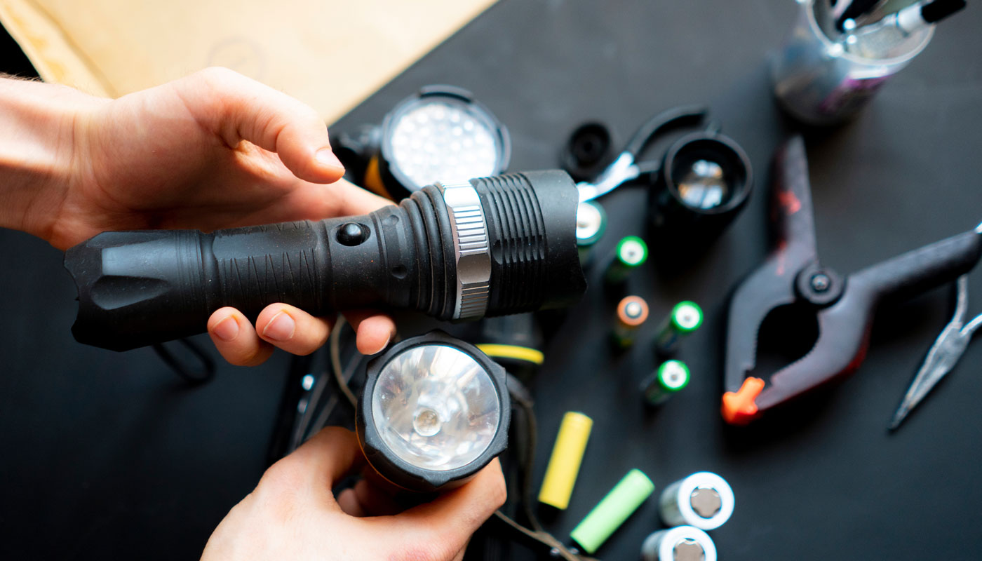 persons hands hold a flashlight with batteries and clamps