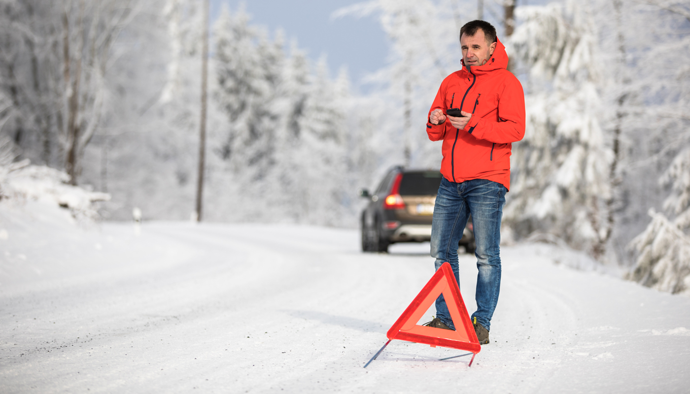 man calling for assistance after his car broke down in the middle of nowhere on a freezing winter day