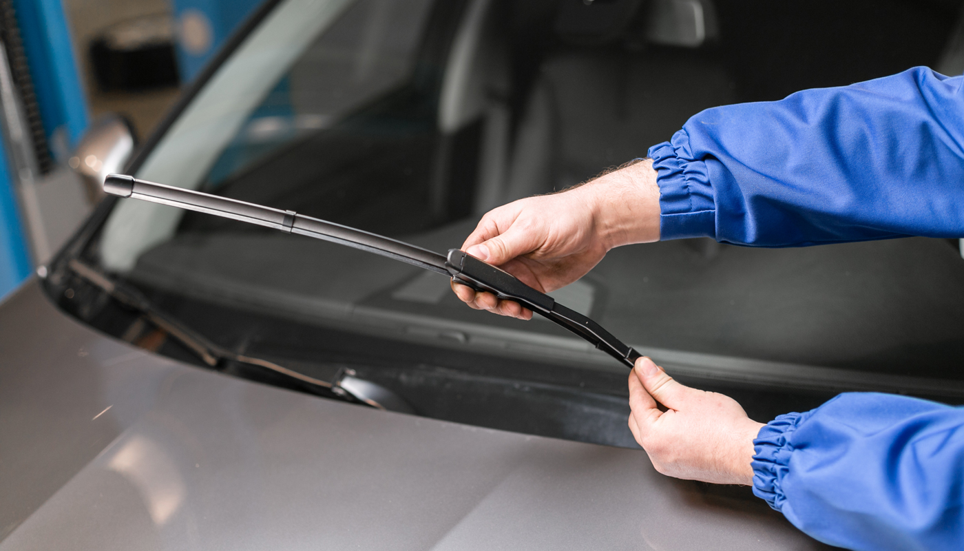 Technician is changing windshield wipers on a car.