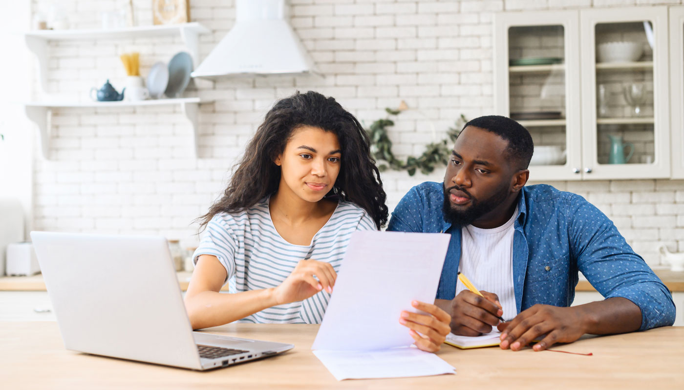 man and woman sitting together on table, studying documents of their family business and working with modern laptop