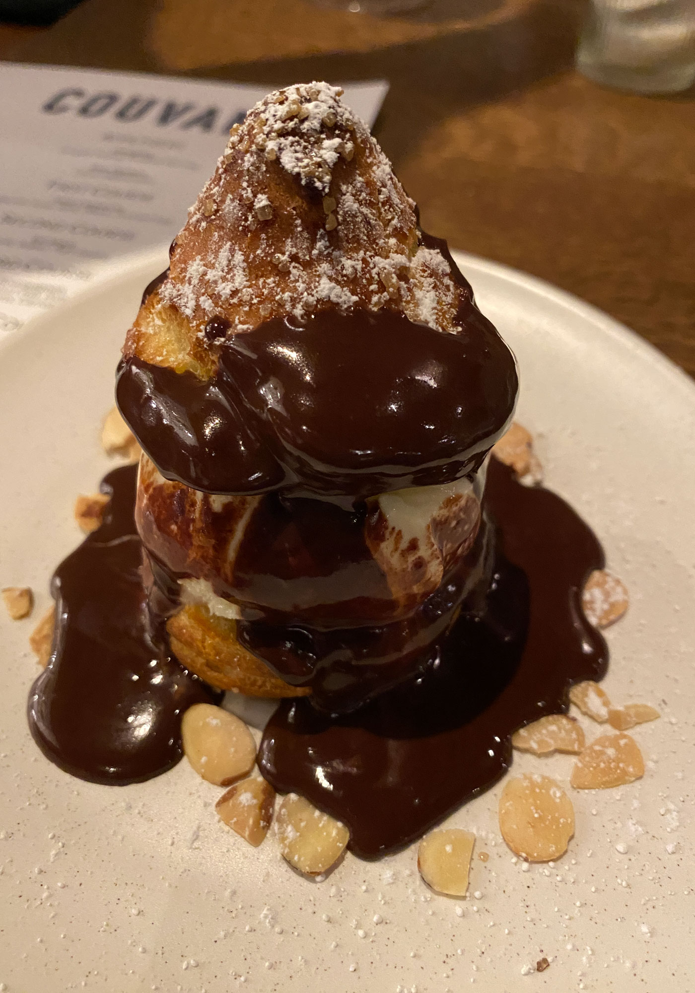 profiterole— halved choux pastry filled with custard, topped with chocolate sauce and sliced almonds— from Couvant, a French brasserie restaurant located in the Eliza Janet Hotel