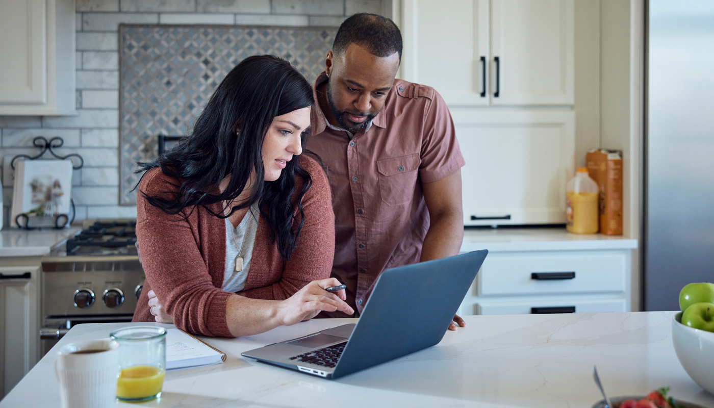 couple reviewing finances on their laptop in the kitchen