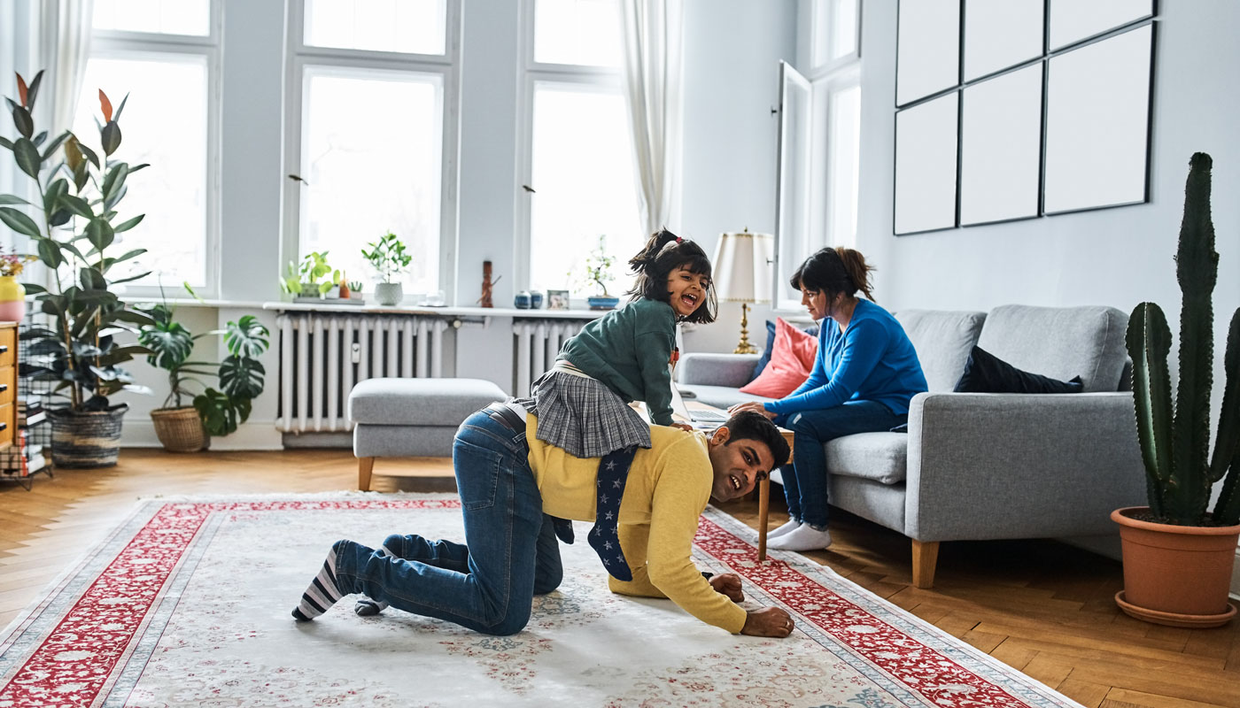 Family in living room while mom is on laptop