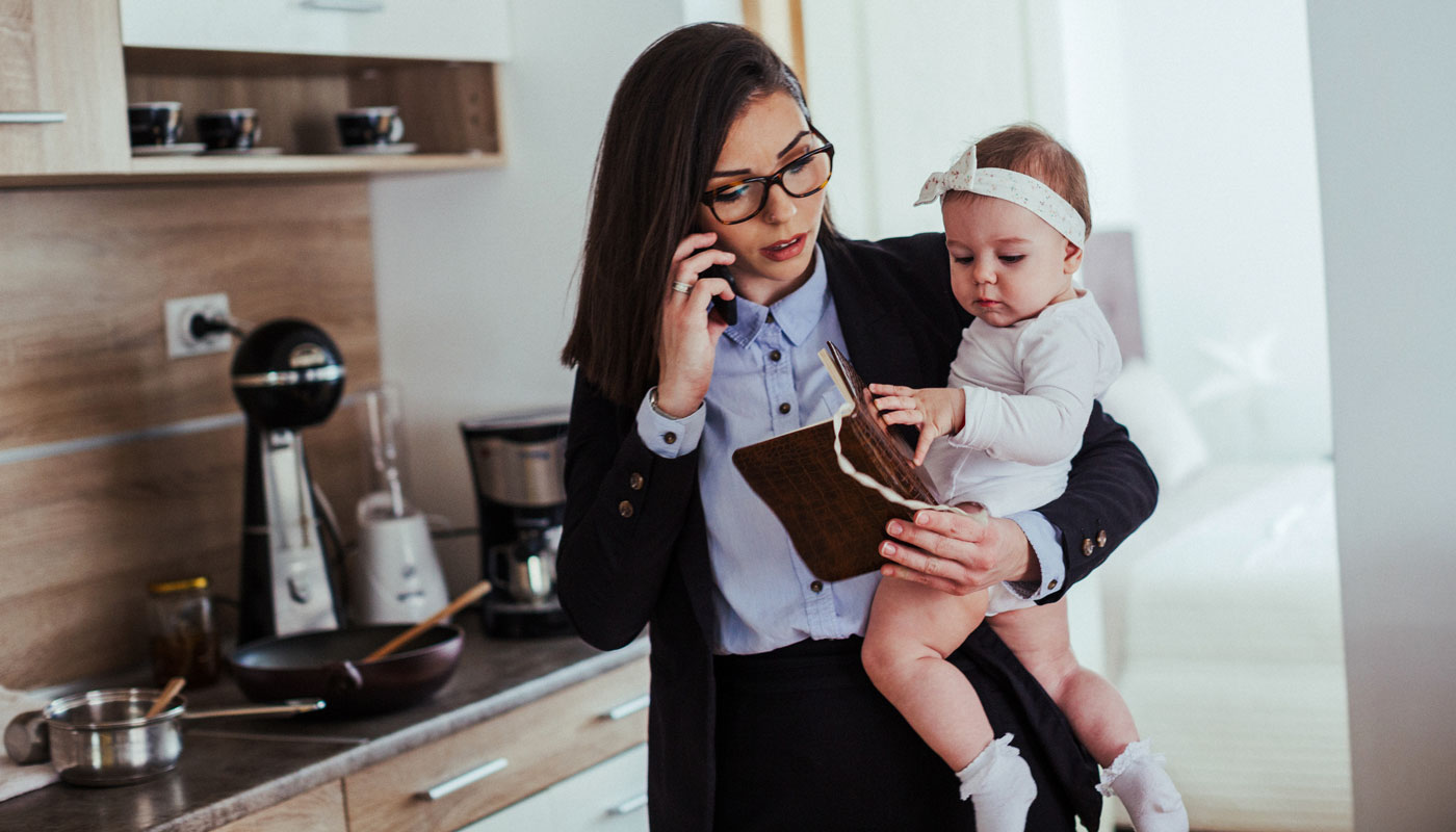 Mother holding baby while in her kitchen dressed for work