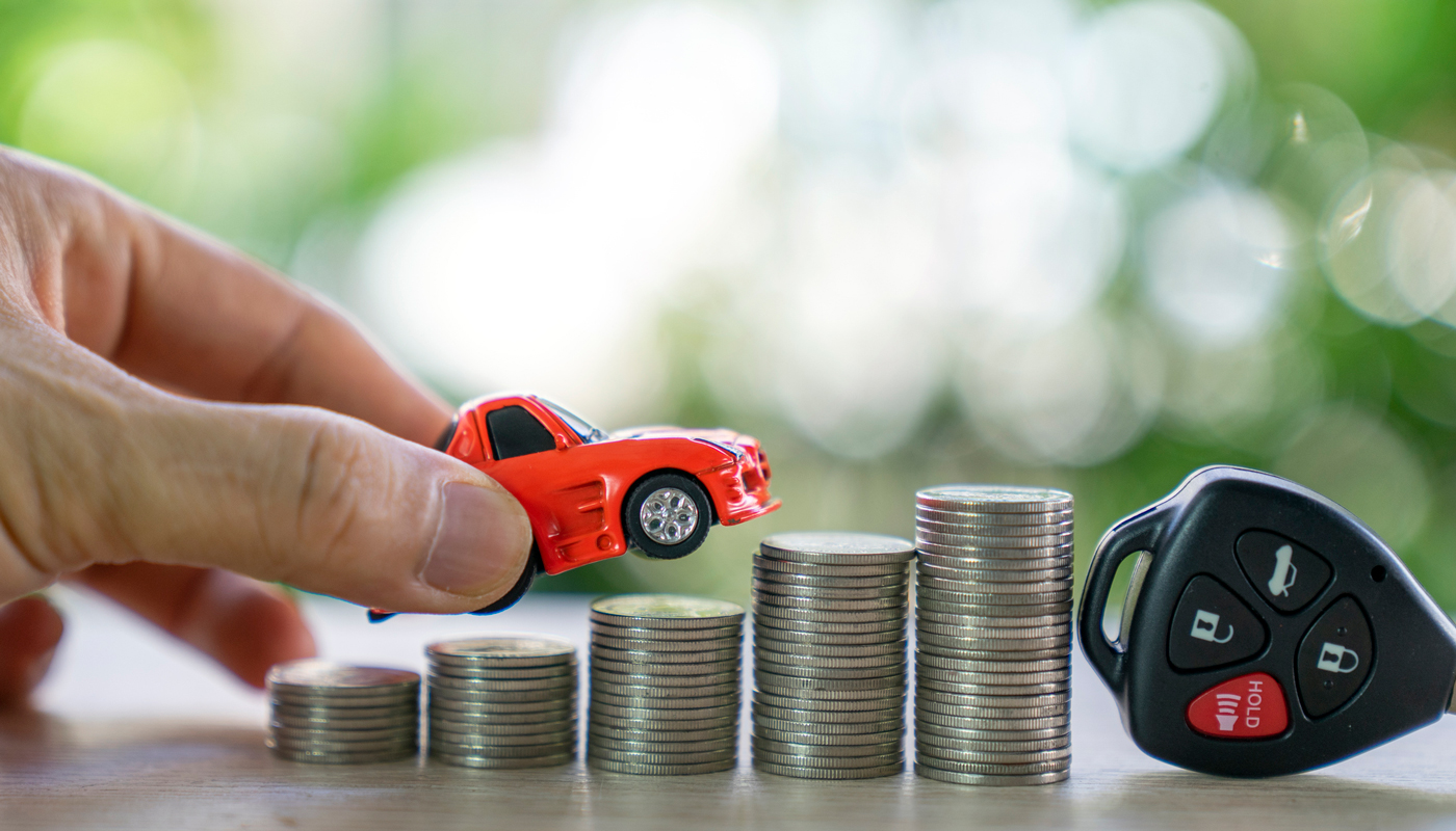 Toy car moving over stacked coins with car keys