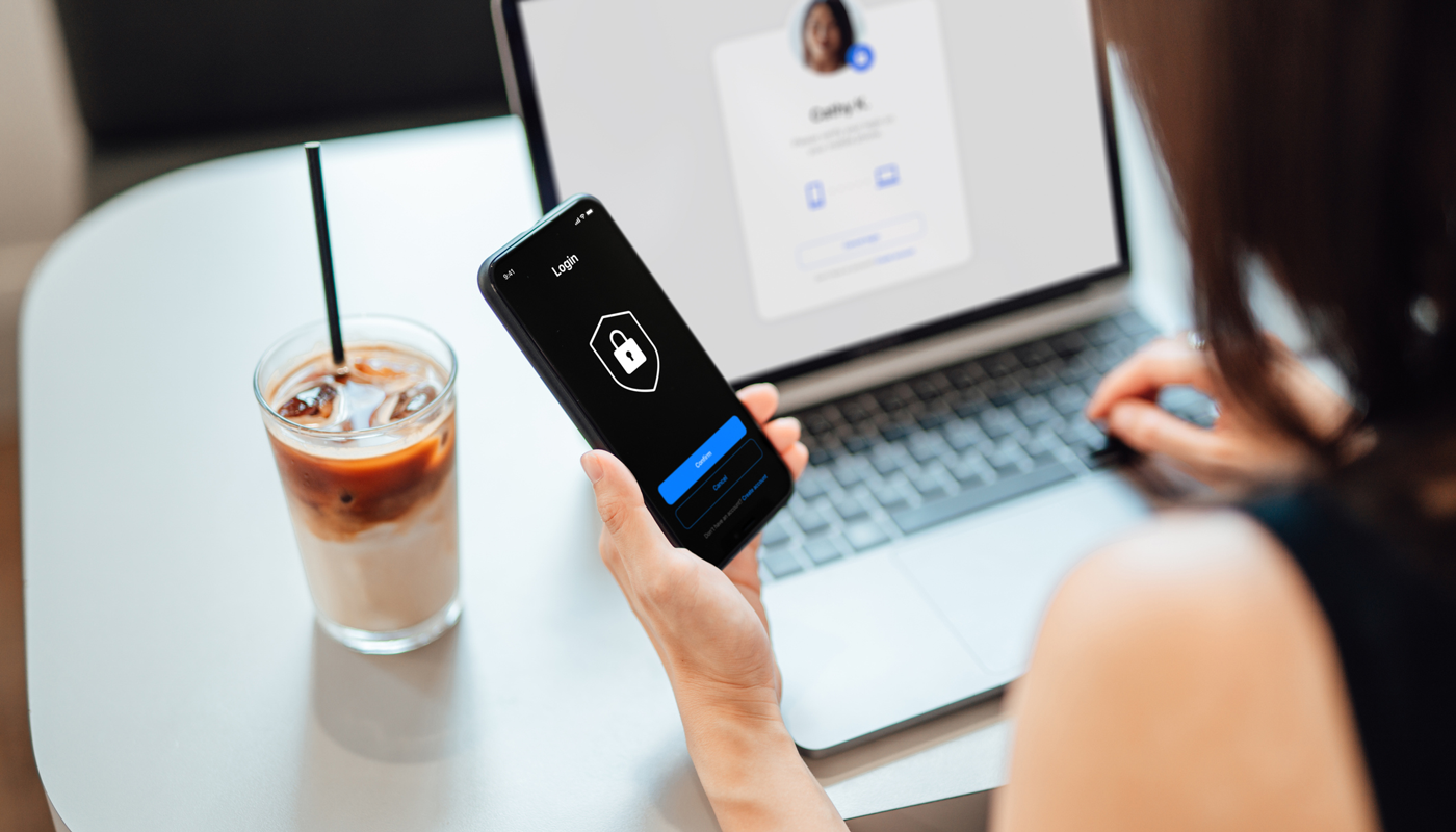 Young Business Woman Logging in Online Security System On Laptop With Mobile App On Smartphone