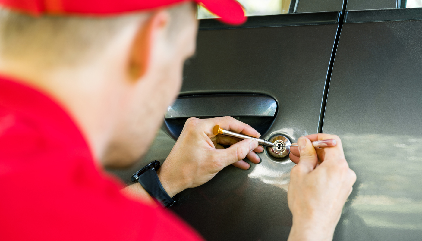 locksmith opening car door with lockpicker