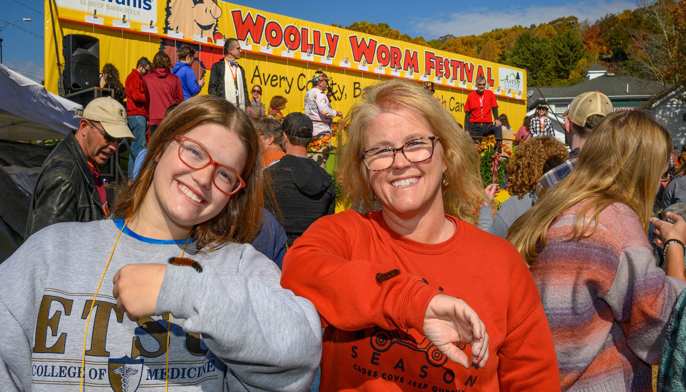 Two women holding worms at the Woolly Worm Festival 