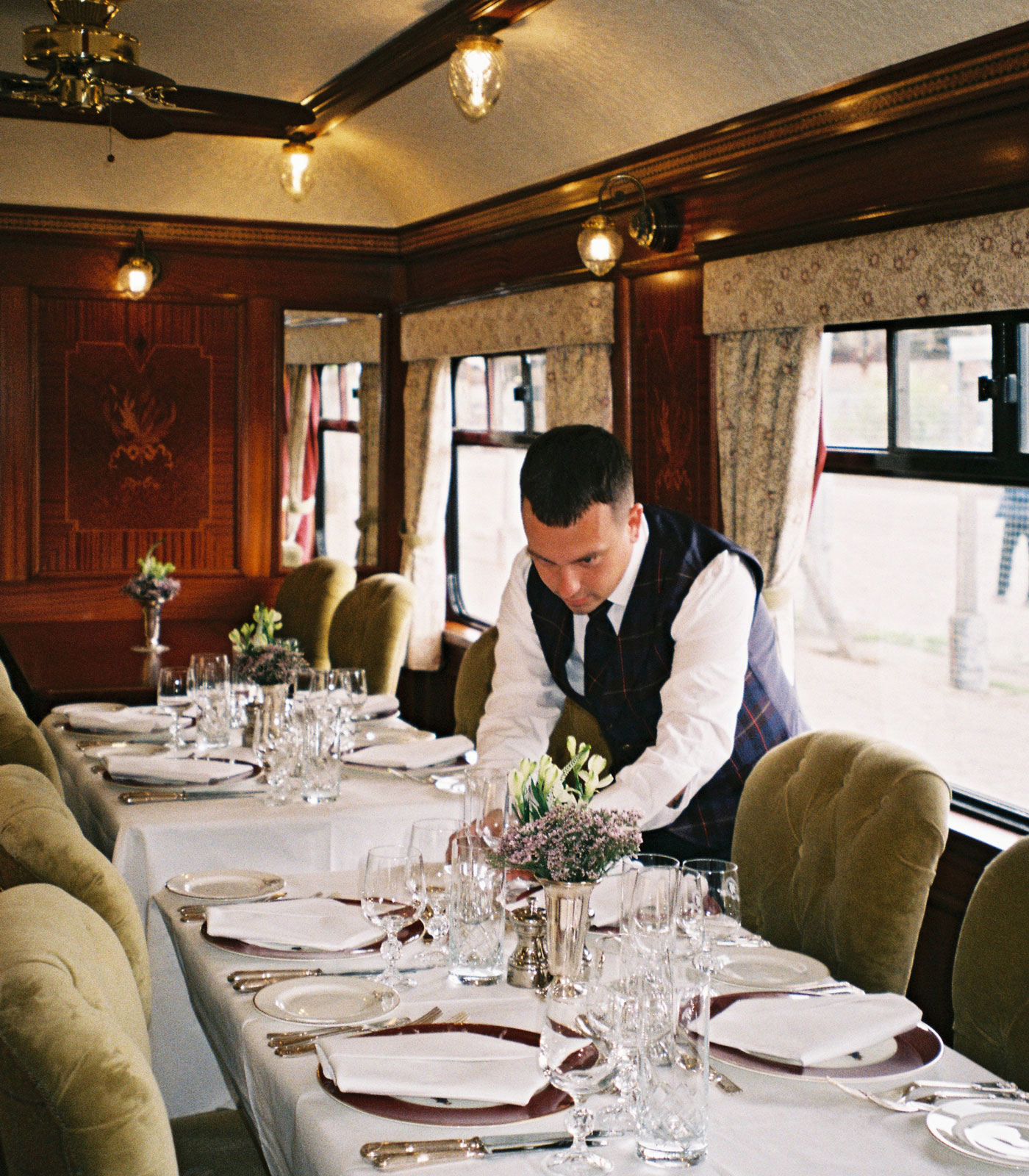 staff member aboard the Belmond Royal Scotsman prepares the dining car 