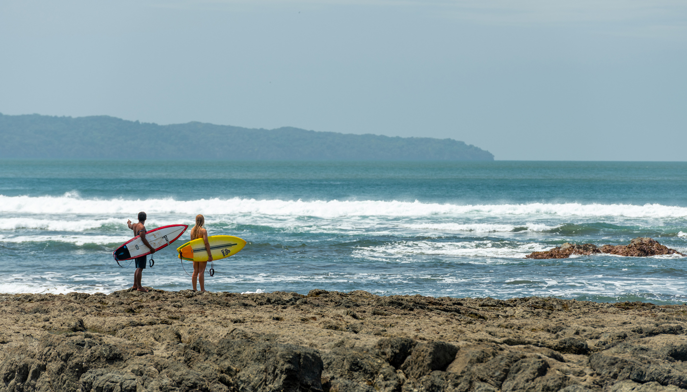 Picture of Panama beach with two surfers at the water's edge.