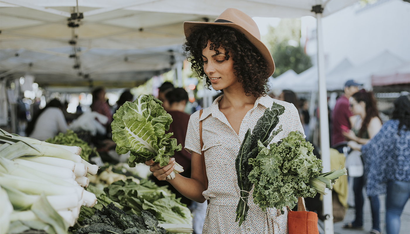A woman buying kale at an outdoor farmers market