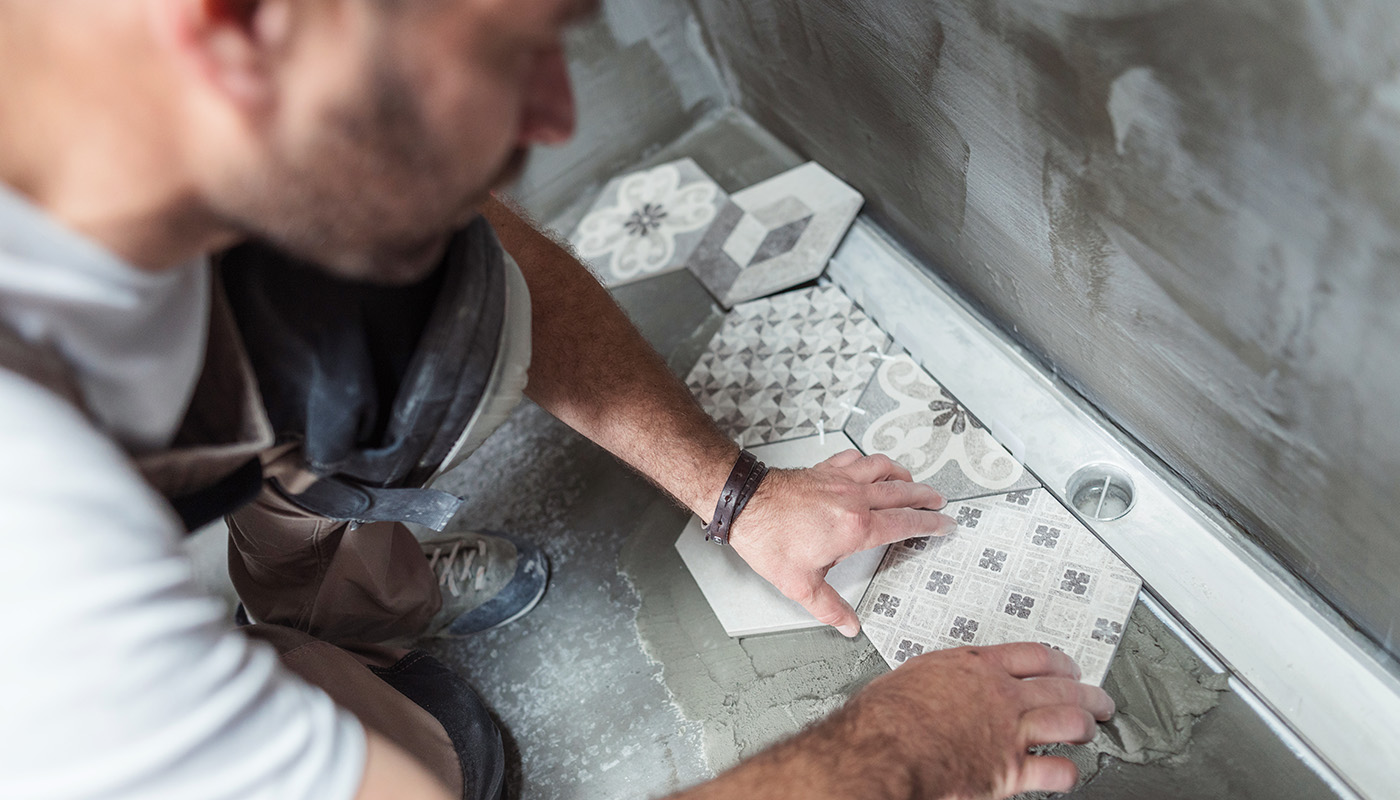 A person installing octagonal tiles in a bathroom. 