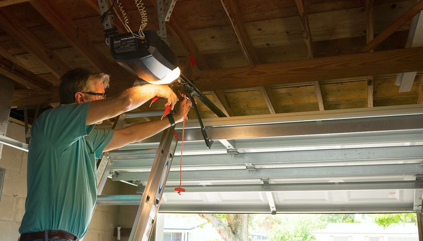 Man on ladder installing garage door