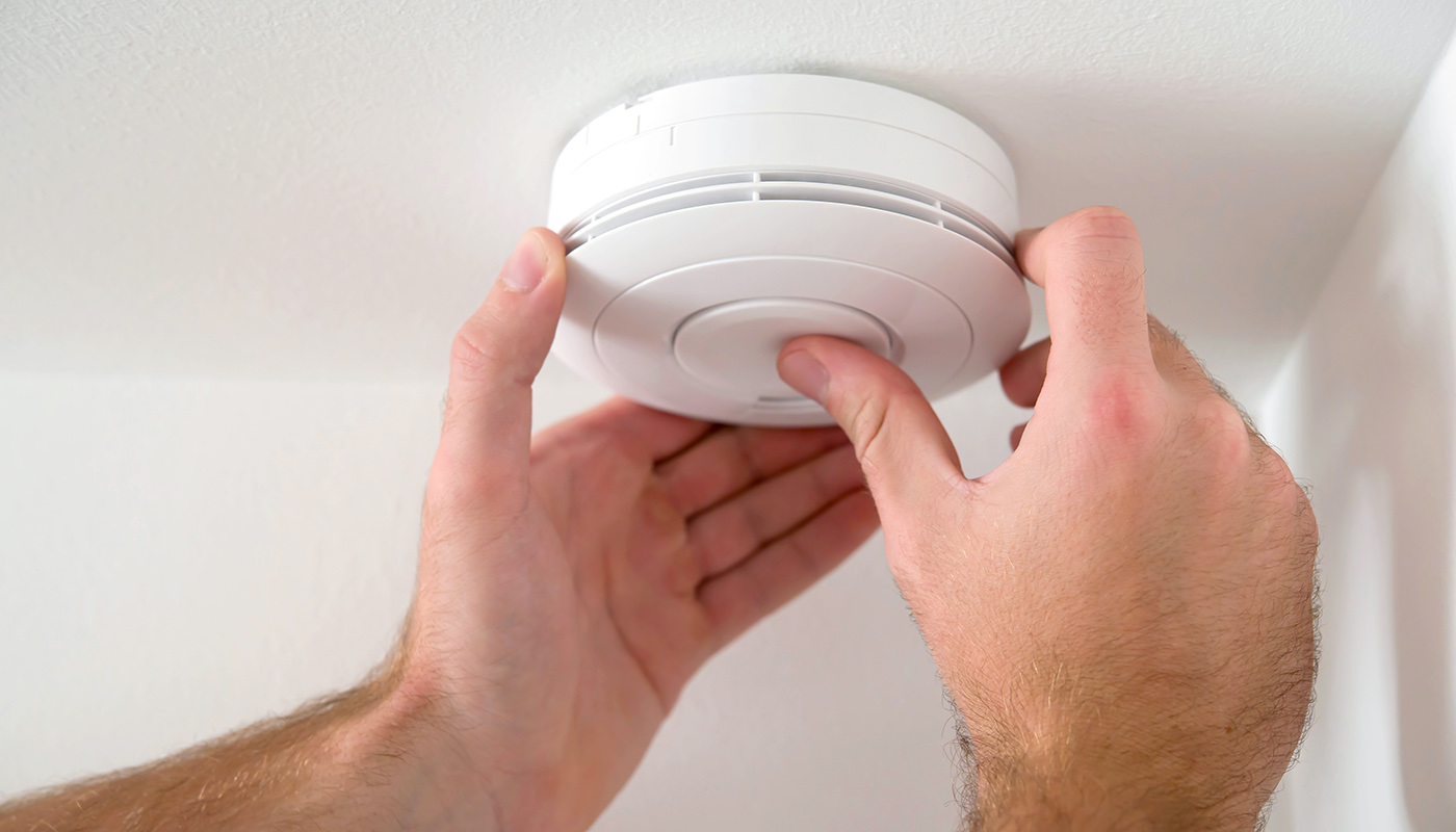 Close up view of a man's hands as he is Installing a smoke detector.