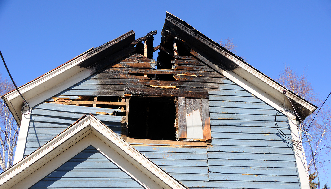 Blue wooden home with the roof burned away
