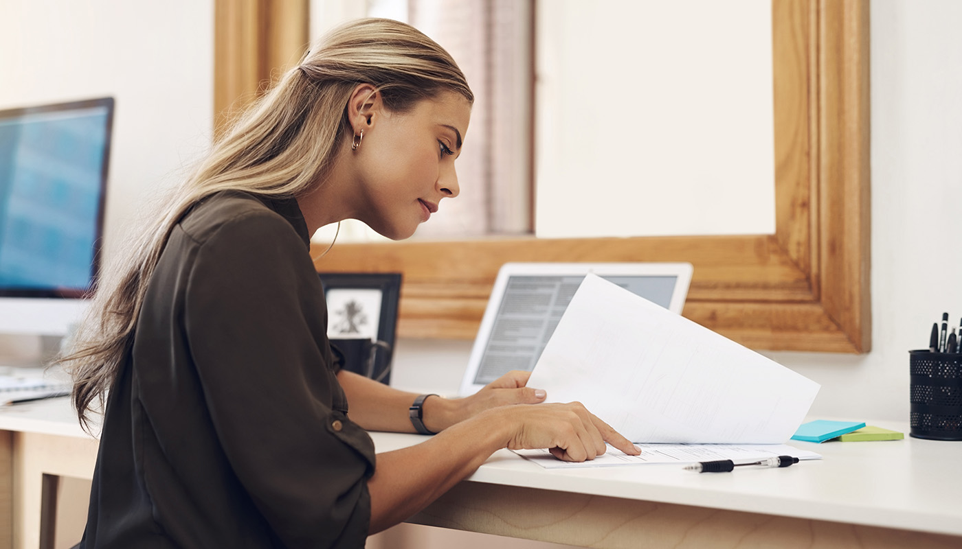 Woman looking at paperwork in front of laptop