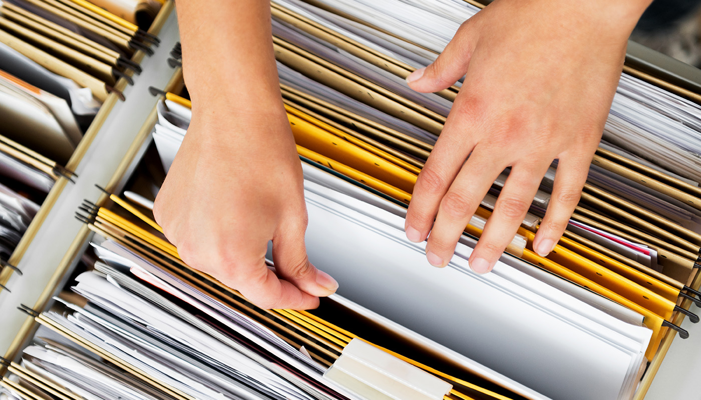 Overhead photo of hands going through file folders in a filing cabinet