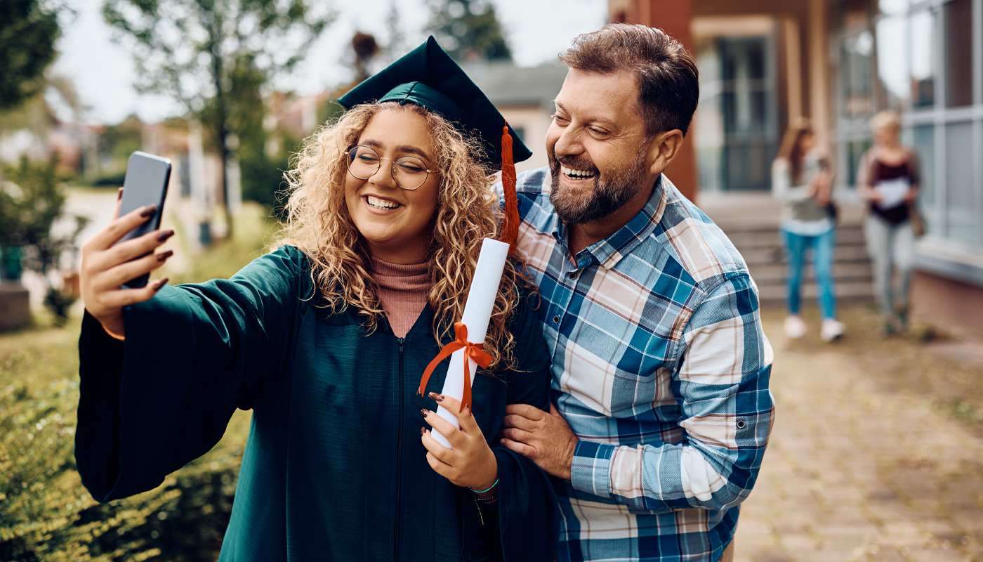 University graduate and father taking selfie with smartphone