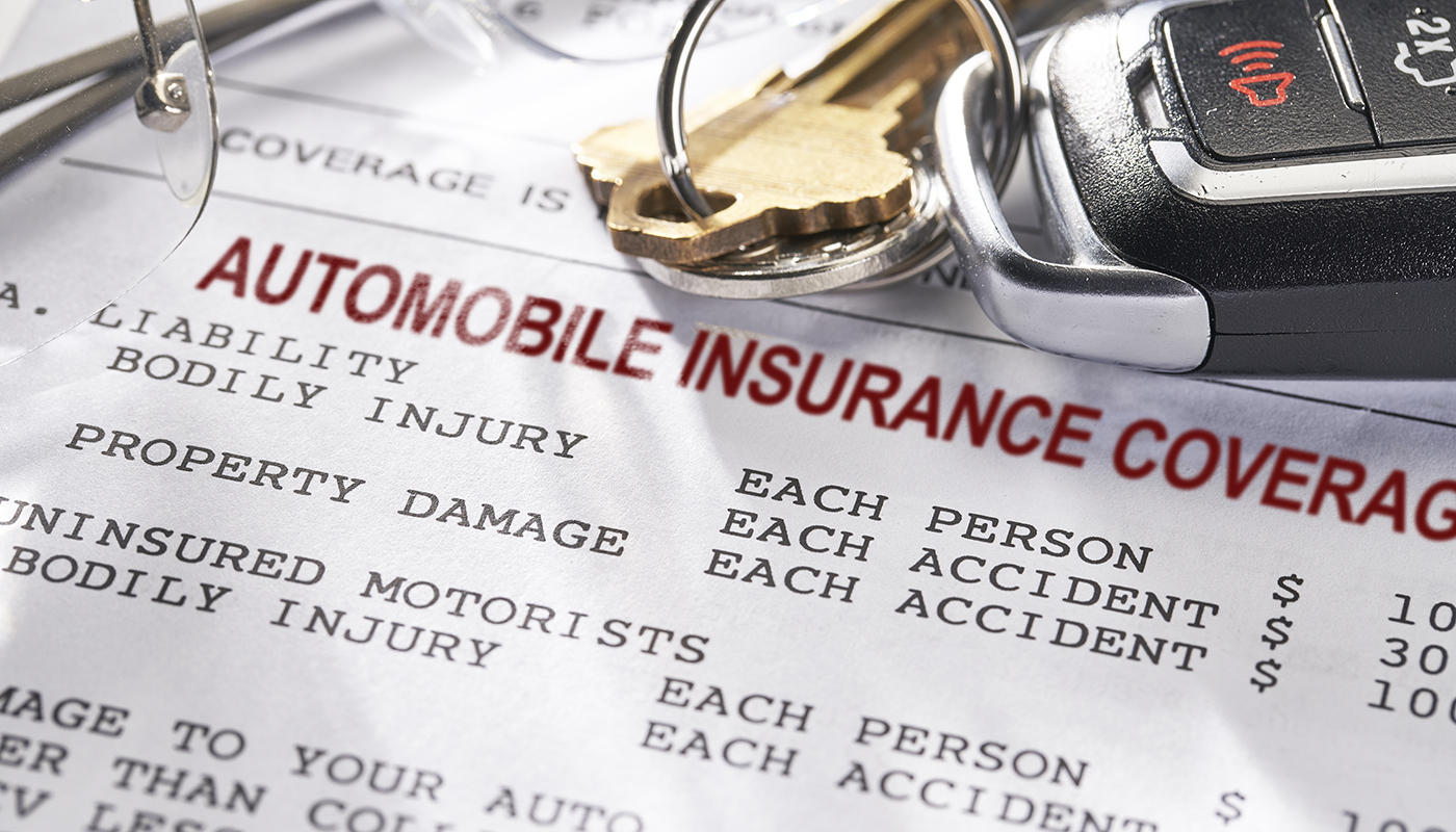 Keys and eye glasses lay on top of a printed sheet of paper that reads, “Automobile Insurance Coverage.”