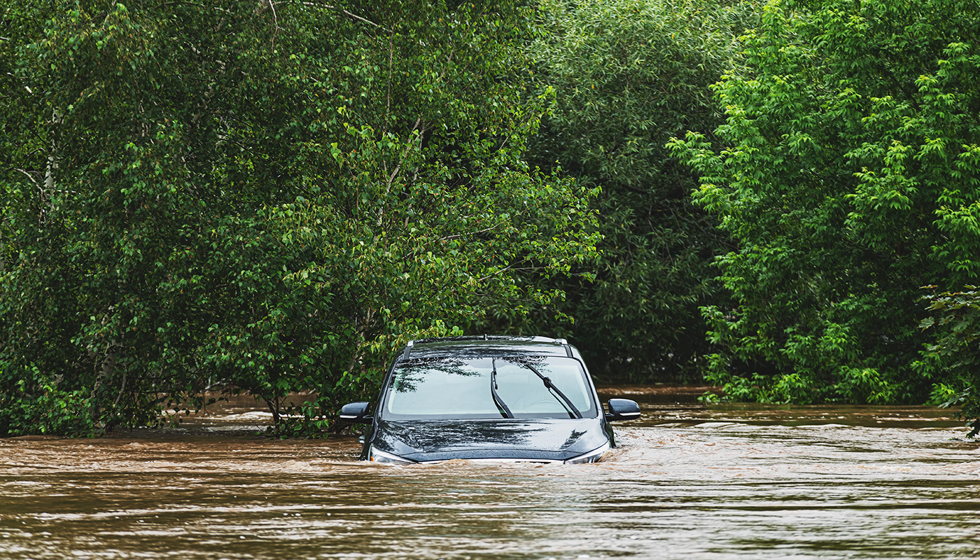 A vehicle is half submerged in water during a flood.