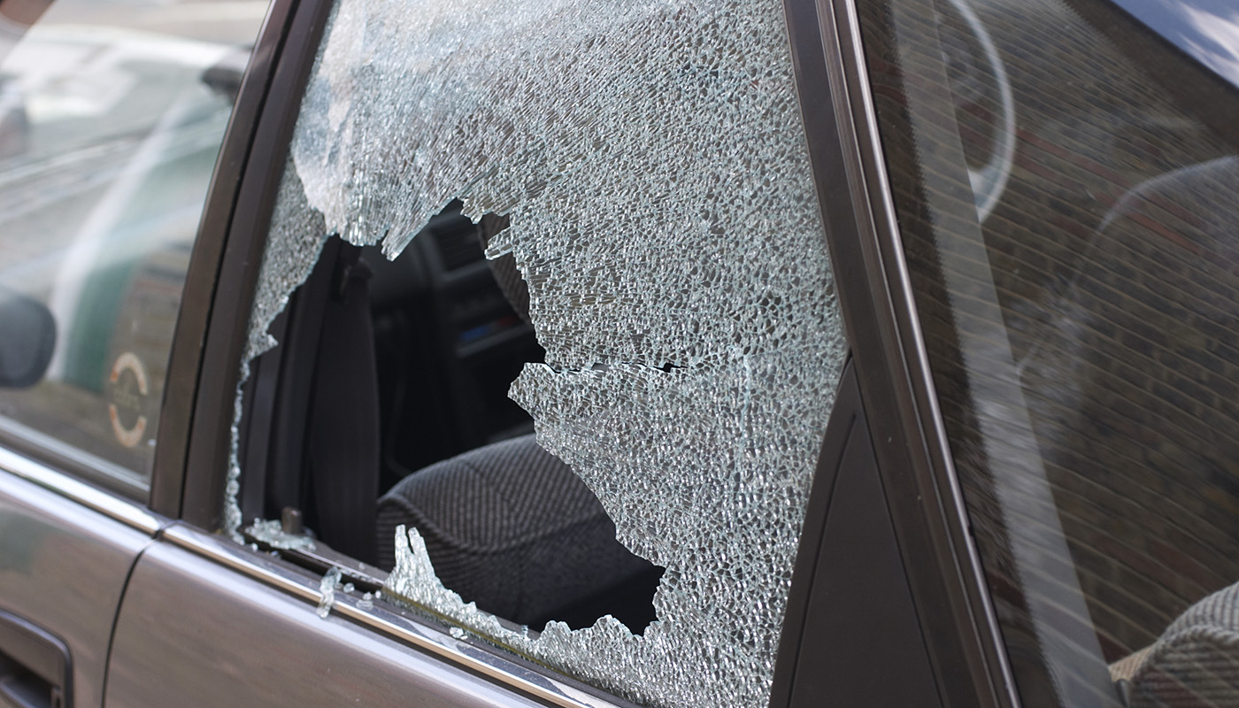 A close-up of a vehicle with shattered glass in a rear passenger window.