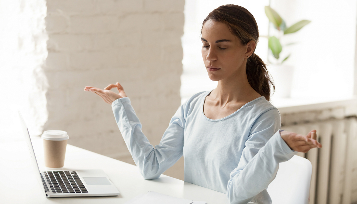 Photo of woman meditating in front of laptop