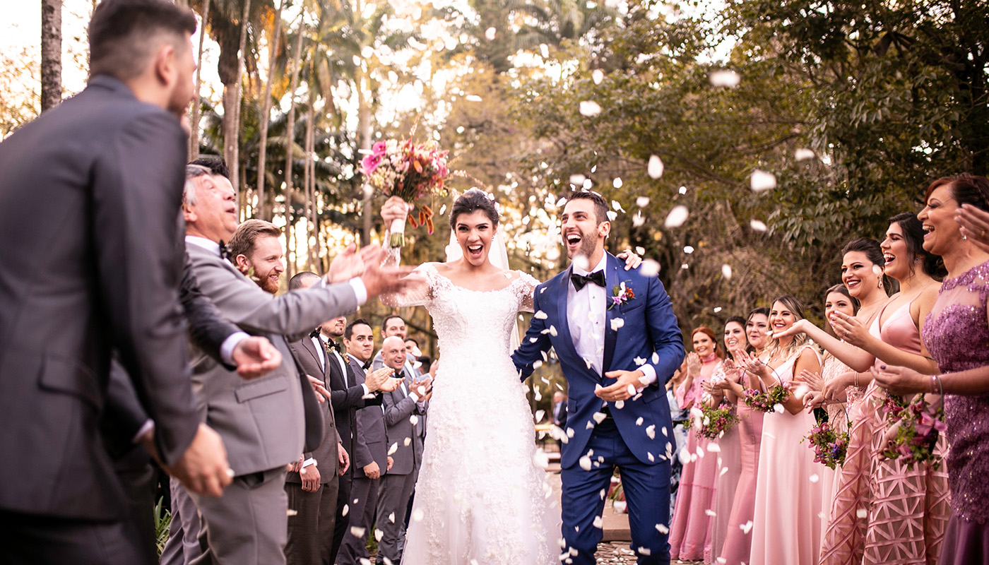 Latin American bride and groom walking outside as guests throw confetti