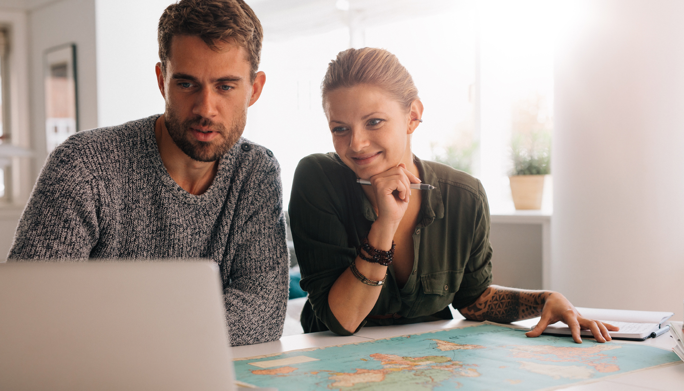 Man and woman planning a trip in front of a map and laptop