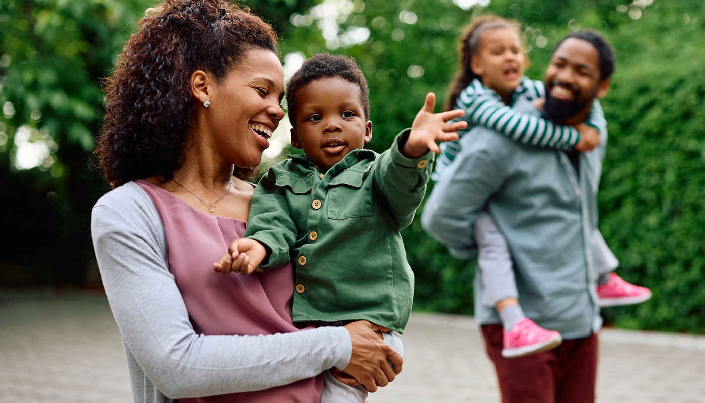 A woman holds her son and a man carries his daughter on his back 