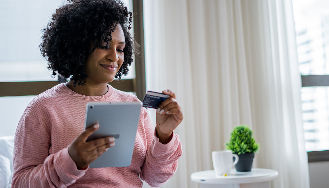 African American woman shopping online with a credit card using a digital tablet