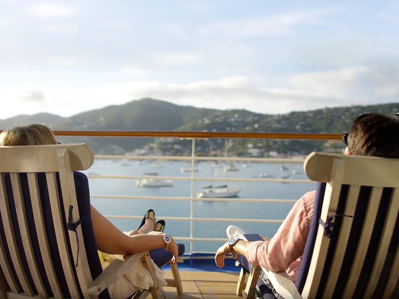 two people sitting in chairs on deck of cruise ship
