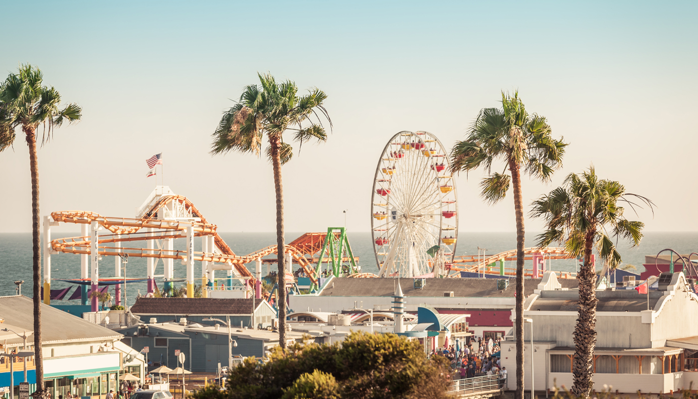 Rollercoaster and ferris wheel at Santa Monica Pier on a sunny day
