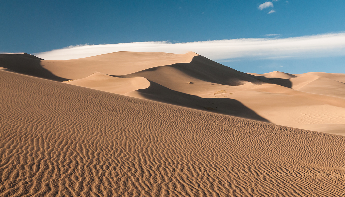 Large sand dunes under a blue sky.