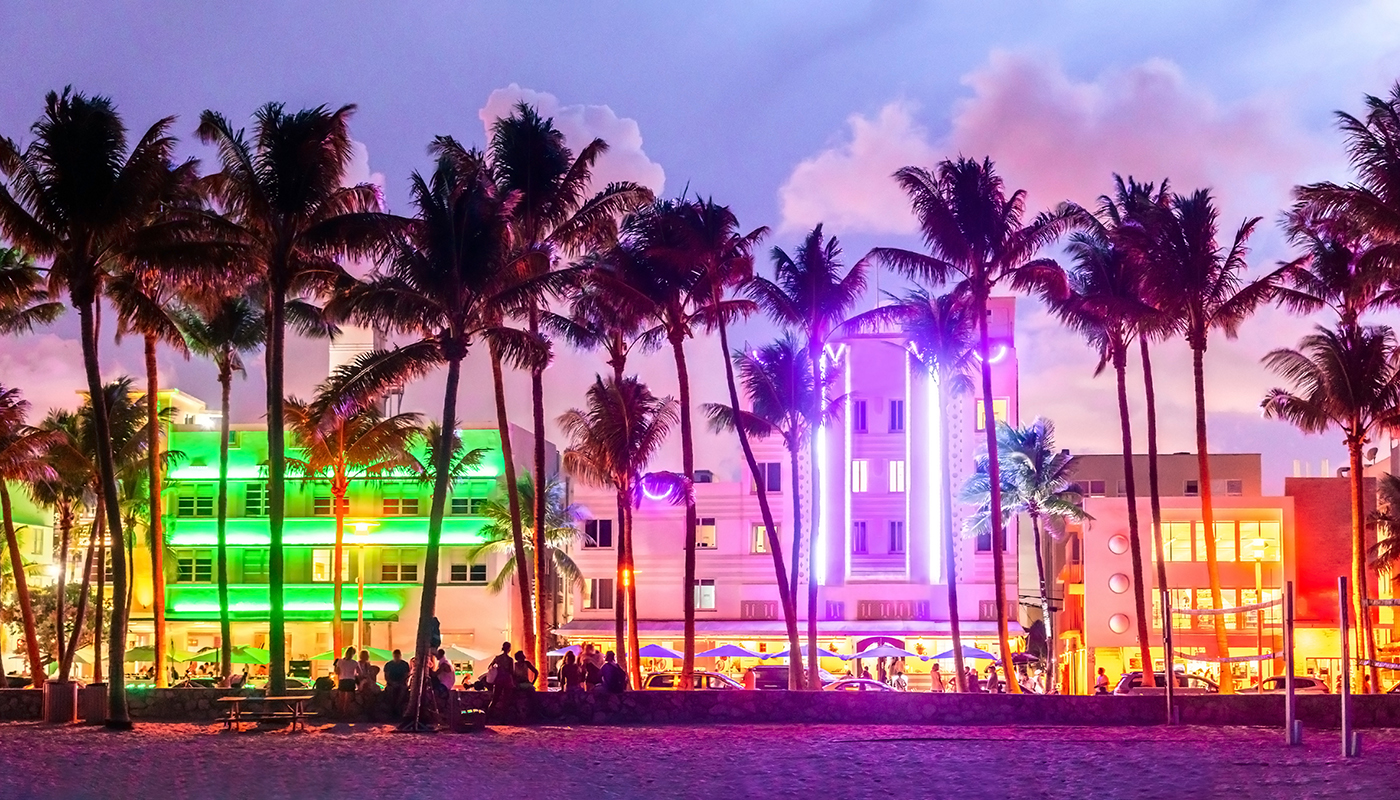 Miami Beach Ocean Drive hotels and restaurants at sunset. City skyline with palm trees at night. Art deco nightlife on the South beach