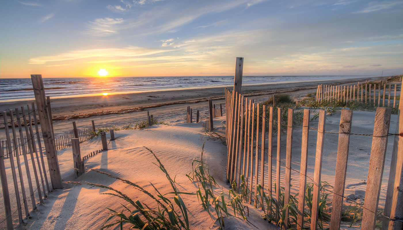 A sandy beach with fencing at sunset in the Outer Banks, North Carolina.