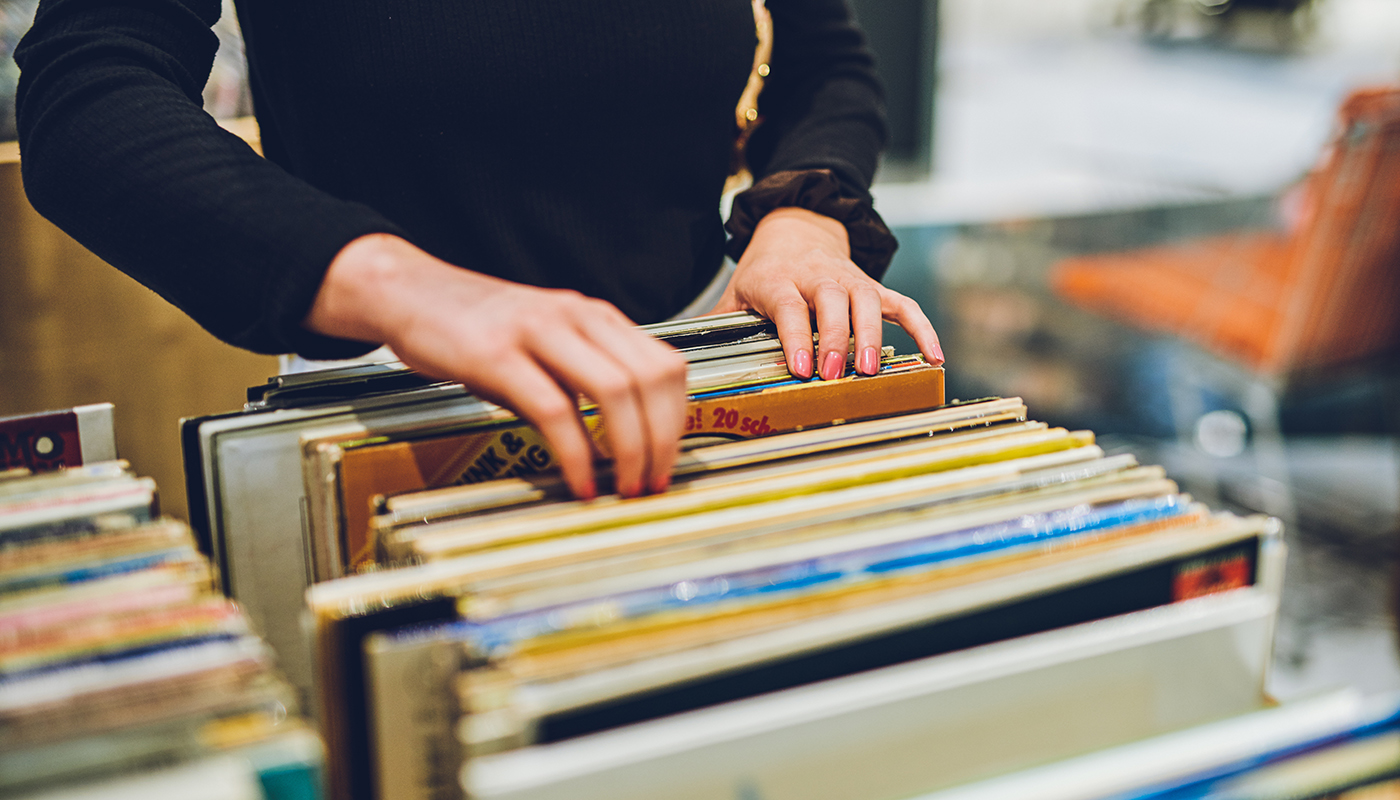 A pair of hands go through a stack of vintage vinyls.