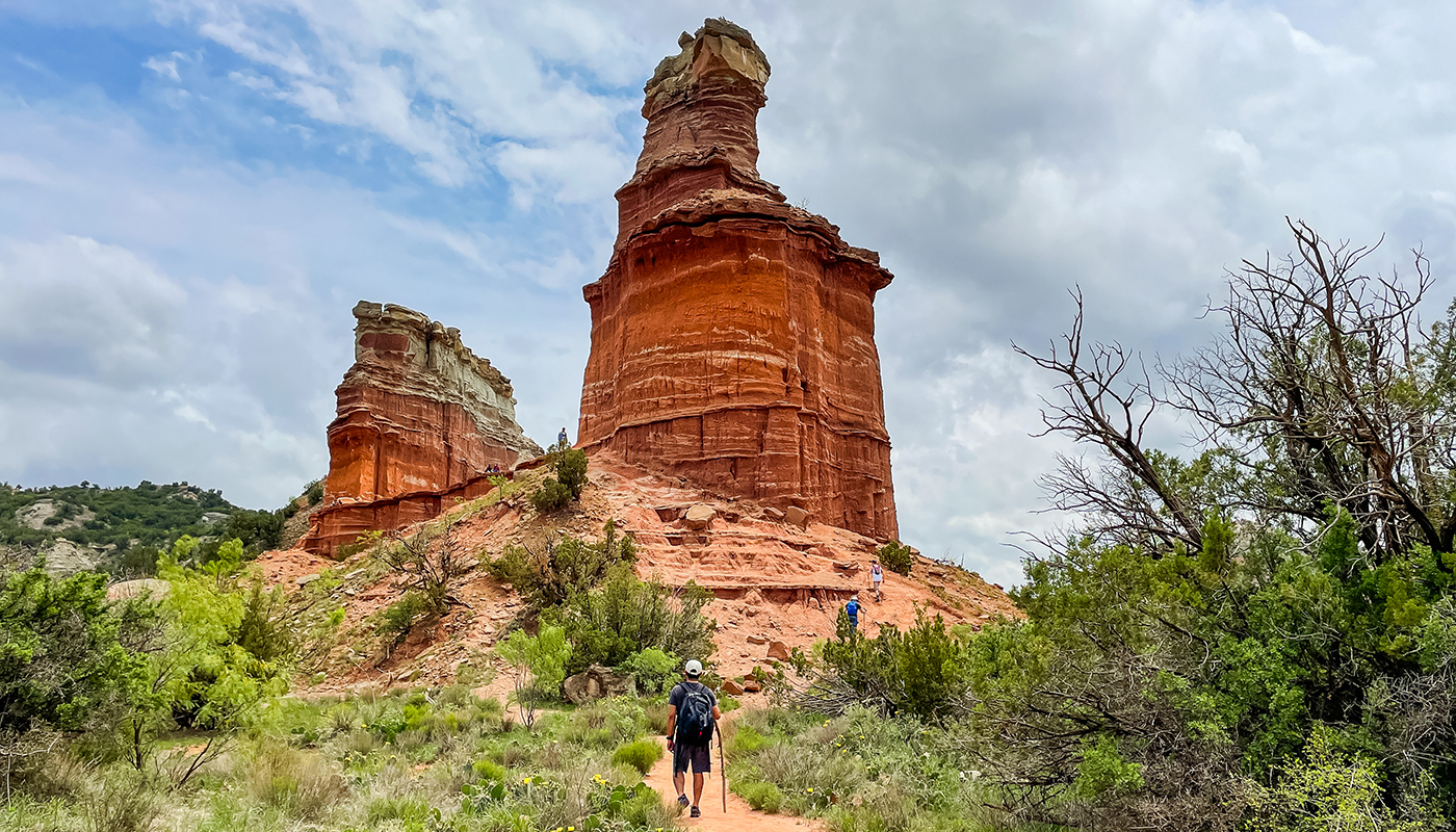 Close up view of Lighthouse symbol rock with visitors walking towards it in Palo Duro Canyon State Park
