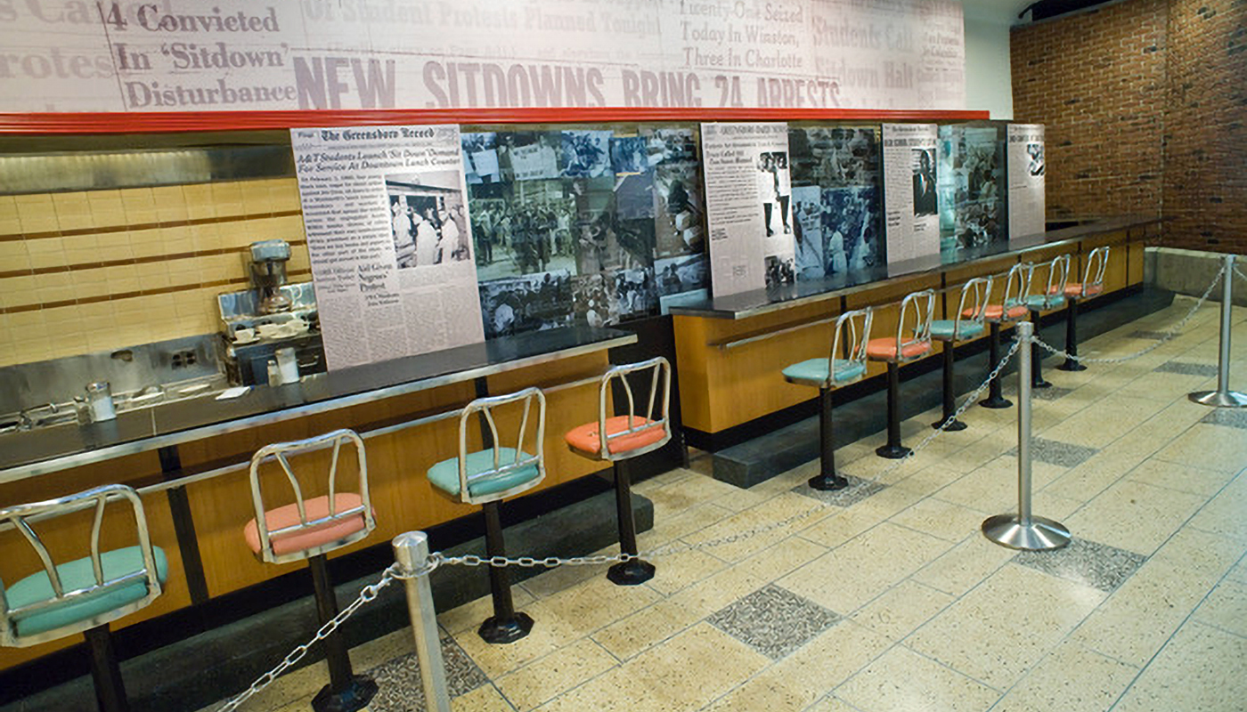 Photo of Woolworth counter and seats with mural in background